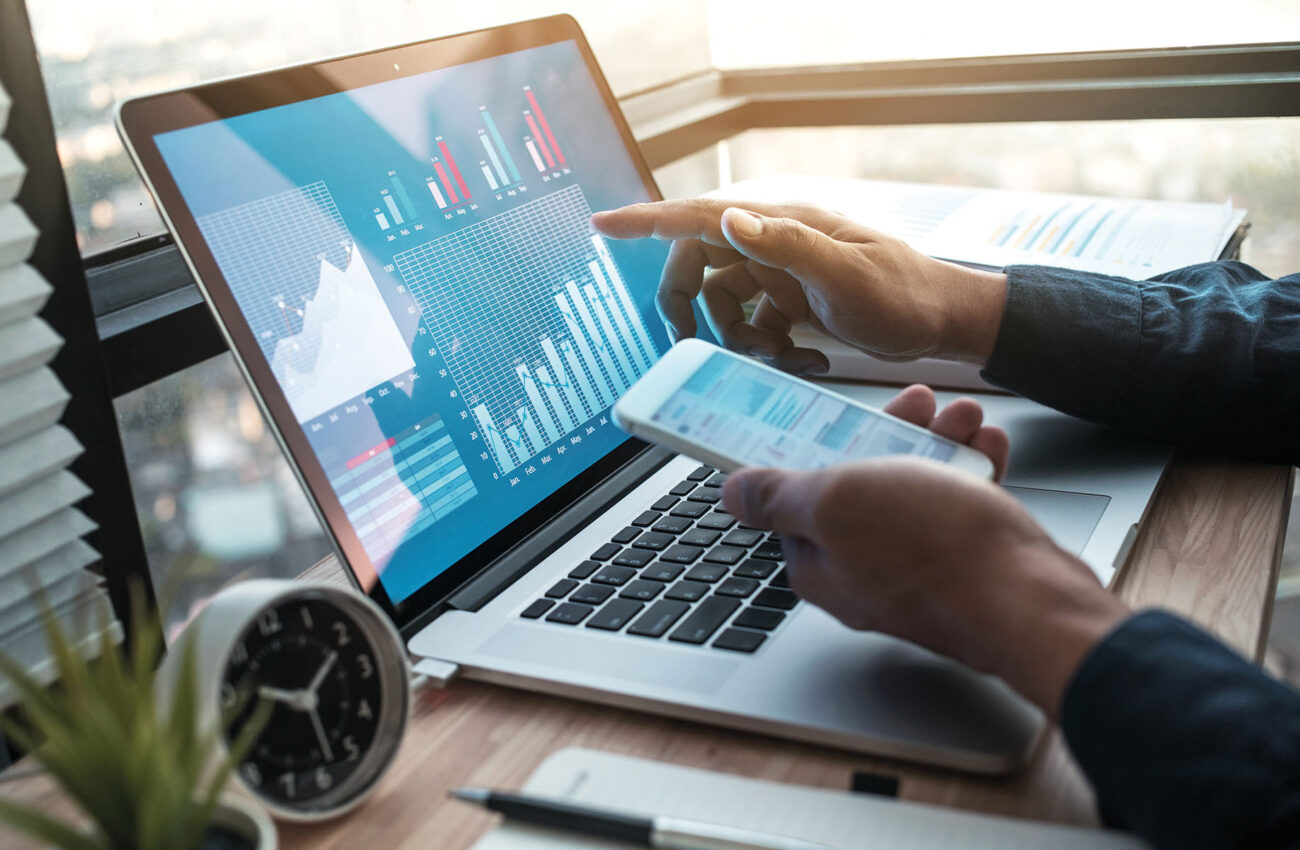 Young businessman working on laptop with diagram graph on comput